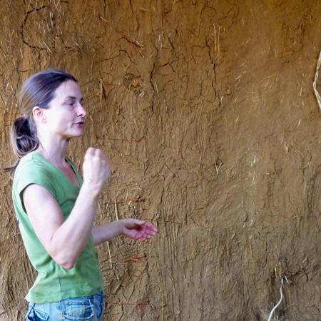 Sigi Koko demonstrates how to plaster straw-bale walls with the first coat