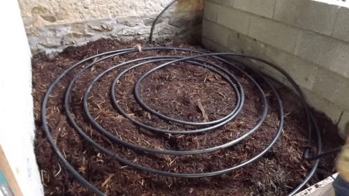 Coils of pipe laid over a layer of litter and bark chippings.