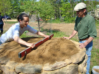 Levelling the sand at the top of the cob oven base