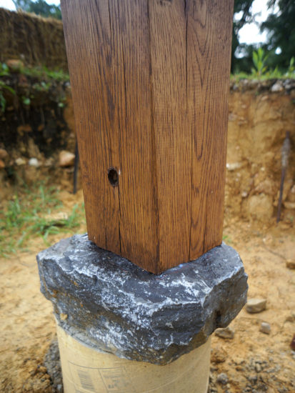 A wooden post scribed into a stone foundation