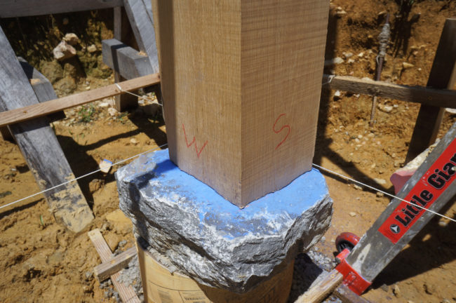Chalk on the stone highlights areas to be removed on the wood post